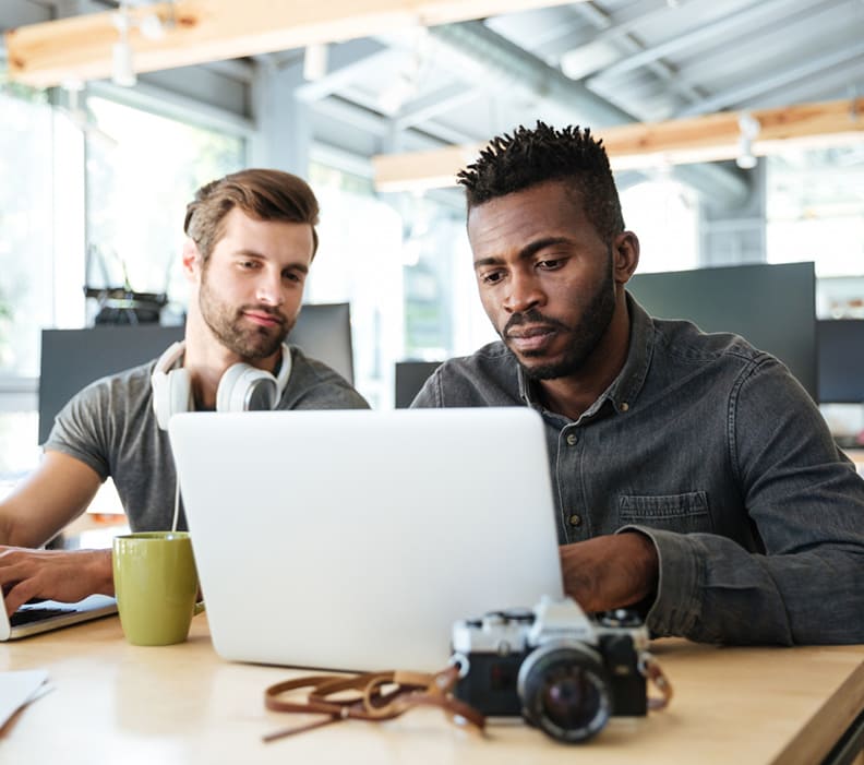 Two colleagues working together on a laptop in a modern office